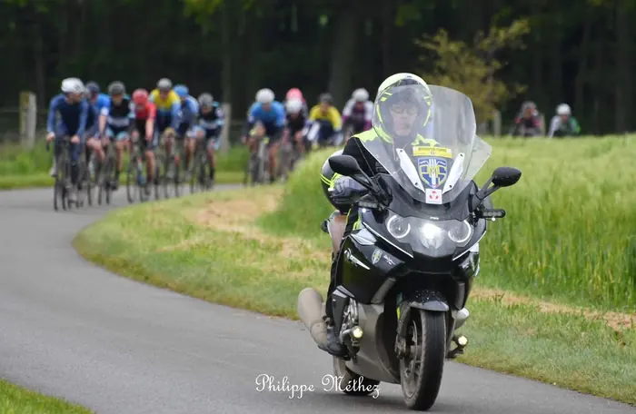 Moto du PMS devant le peloton à travers la campagne