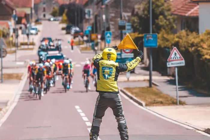 Motard levant un drapeau jaune pour neutraliser un danger