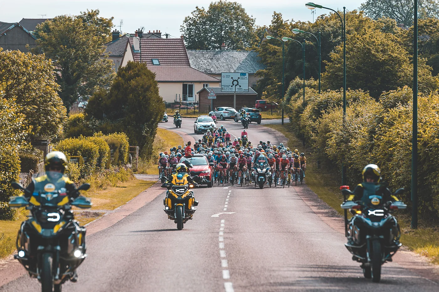 Trois motos du PMS déployées autour du peloton, encadrant la course